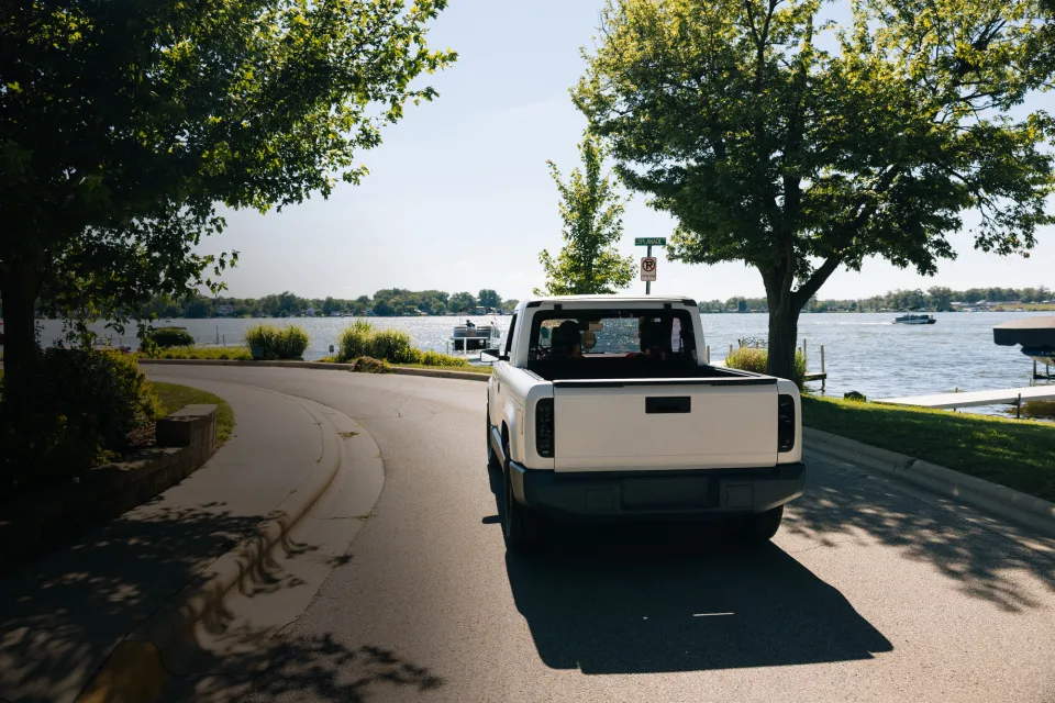 Vista trasera de una camioneta pickup blanca Slate circulando junto a un lago.