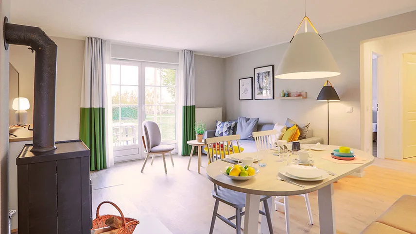 Lägenhetens vardagsrum med soffgrupp, kamin och matbord dukat för måltid.