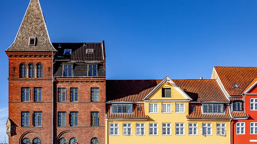 Färgglada stenhus mot en blå, molnfri himmel i Christianshavn.