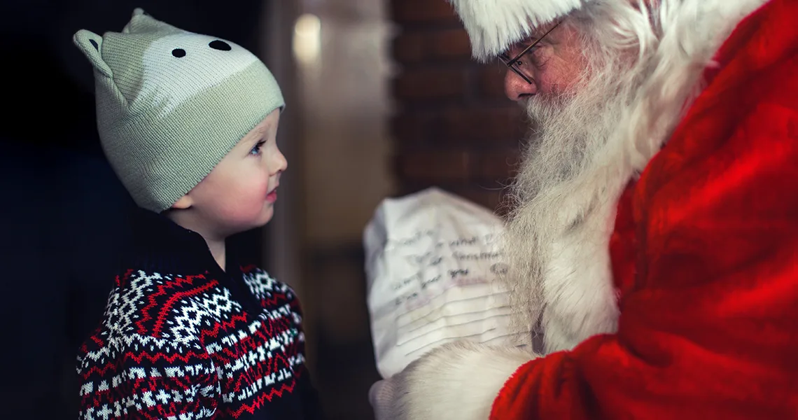 Litet barn lämnar önskelista till jultomten på julmarknad i Köpenhamn. 
