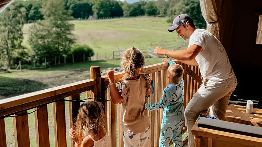 Familie kigger ud over parken fra Wild Lodge hos Skånes Djurpark