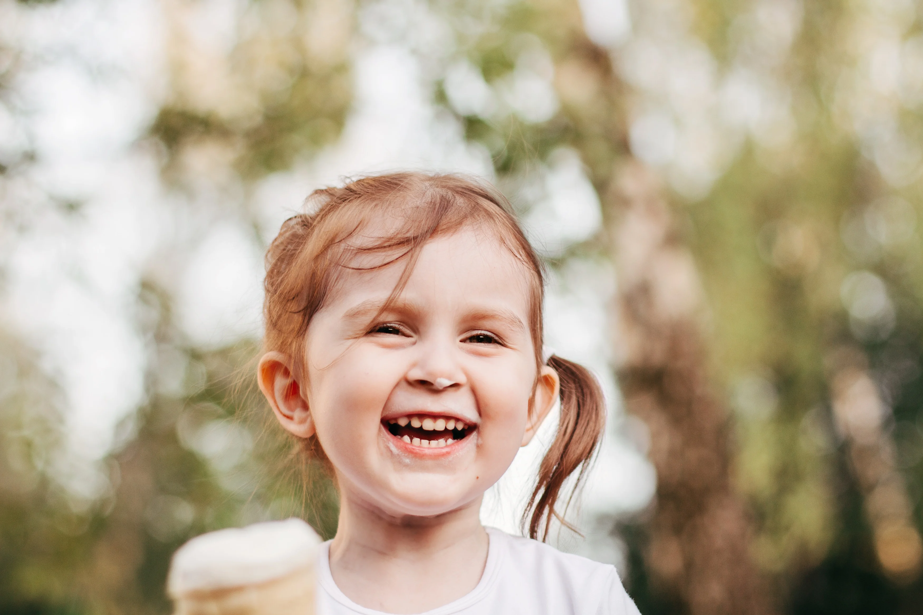 Litet barn som skrattar och äter glass.