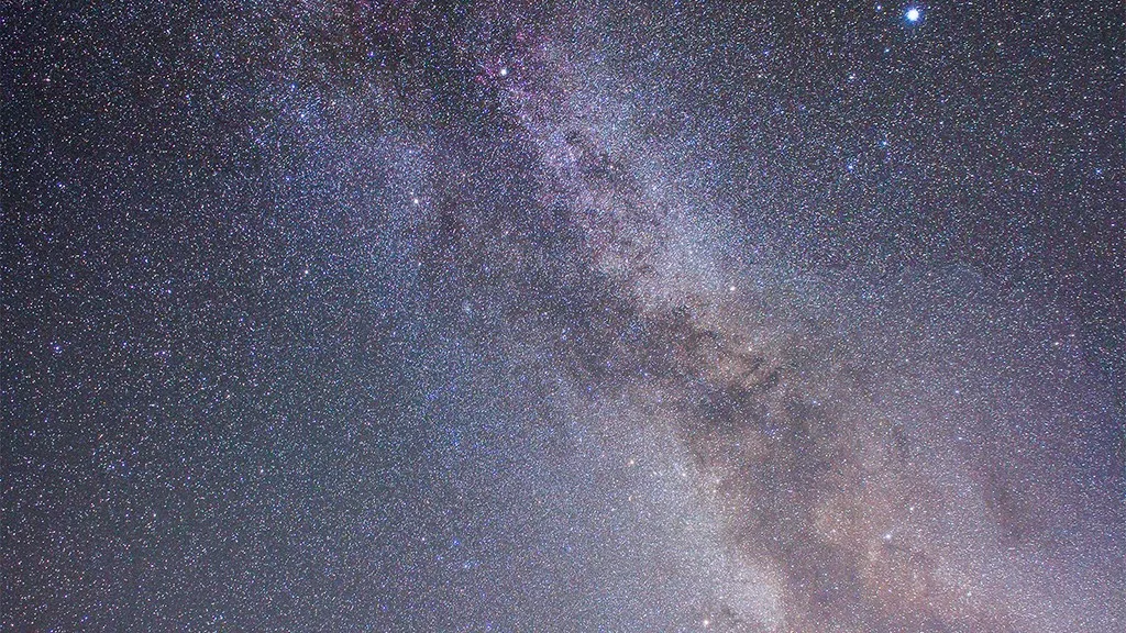 Stjärnor lyser klart på natthimlen och bildar Vintergatans stråk.