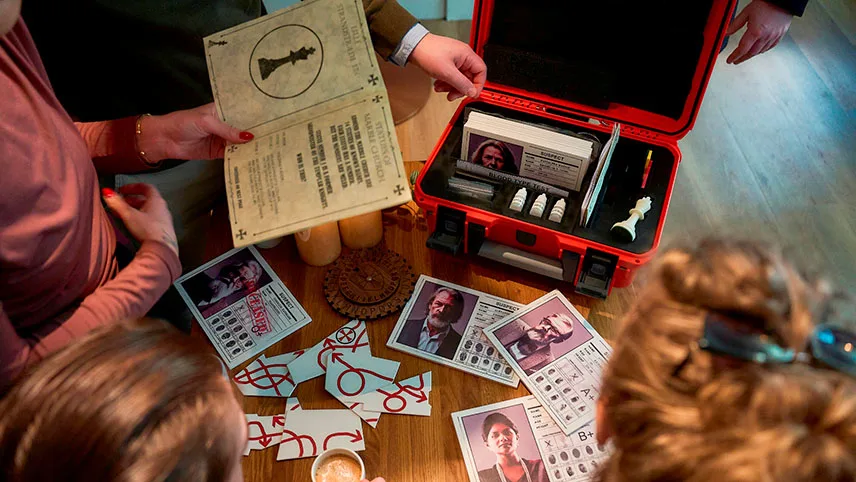 Besökare har öppnat Evidence Suitcase och plockar ut föremål som kort, broschyrer och fotografier på ett bord.