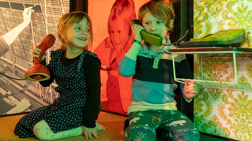 Två barn leker med gamla analoga telefoner inne i museets familjeverkstad.
