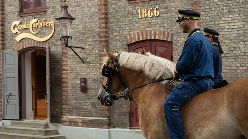 Två av bryggeriets hästar med ryttare utanför ingången.