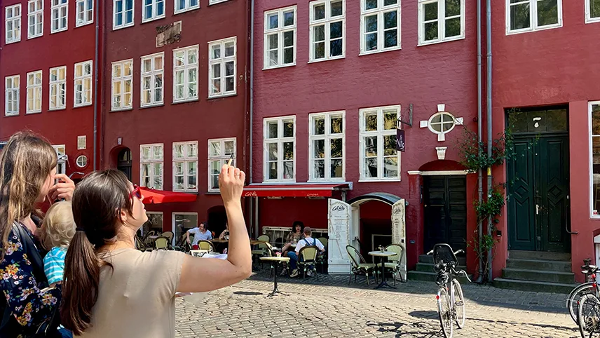 Ett lag utanför färgglada gamla stenhus på ett torg i centrala Köpenhamn.