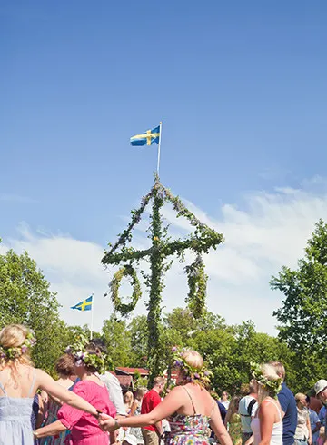 Folk danser om en midsommerstang i Sverige.