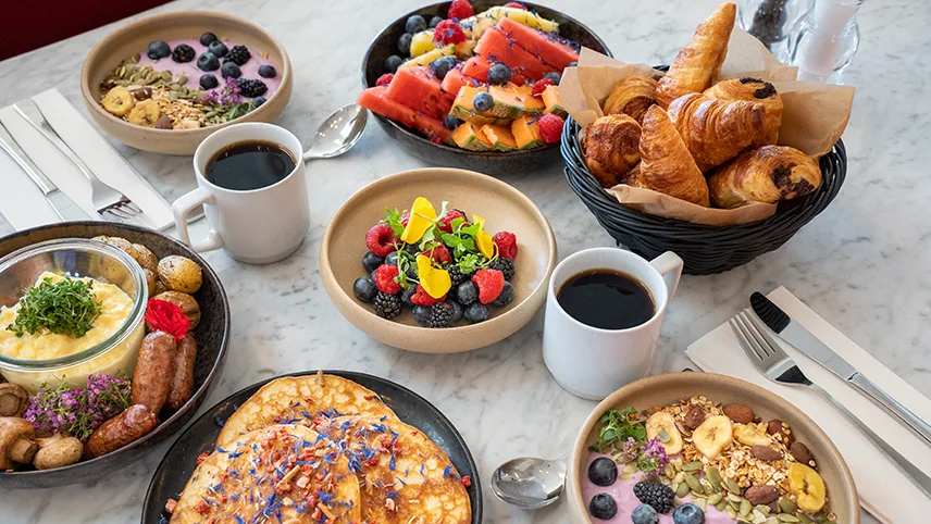 Frukostbuffé framdukad, med kaffe, pannkakor, croissanter, yoghurt och frukt.