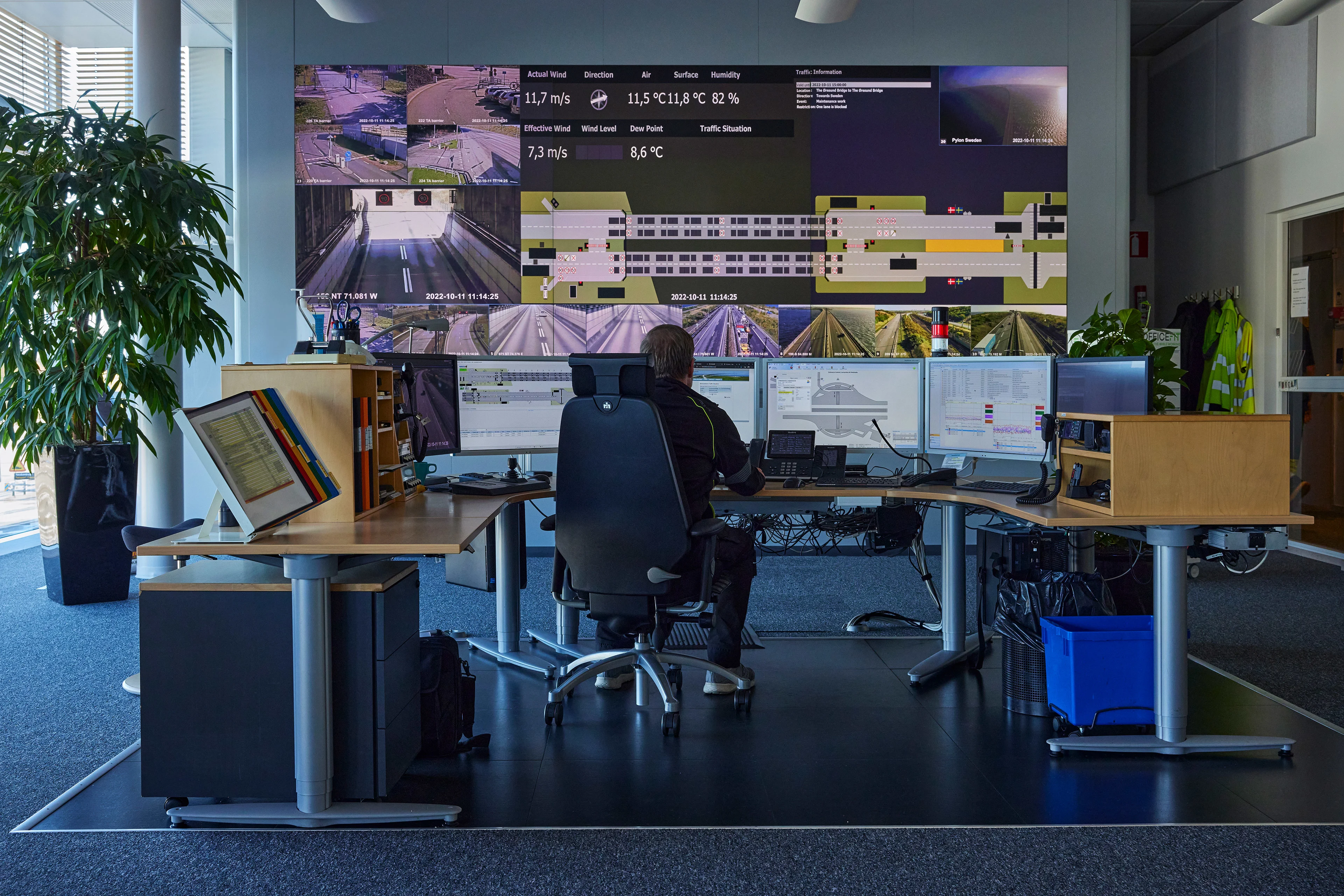 A man sits behind multiple screens, monitoring the trafic on the Øresund bridge 
