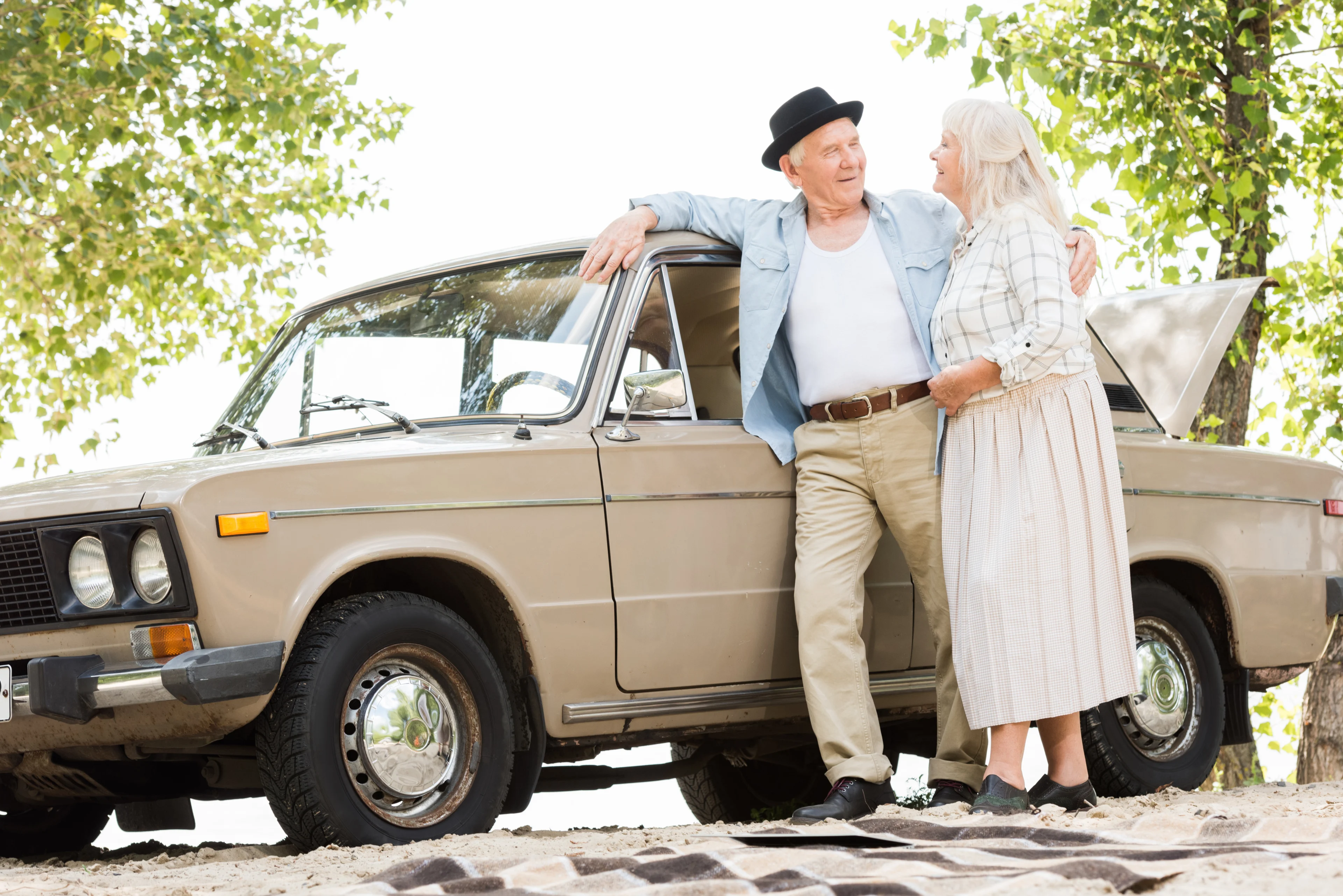 Ett äldre par som står vid en gammal bil.