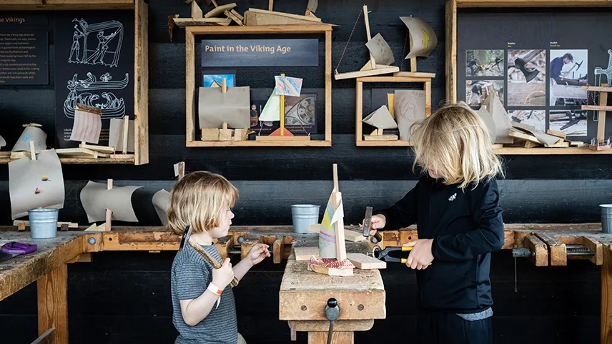 Två barn bygger små träbåtar i museets verkstad.