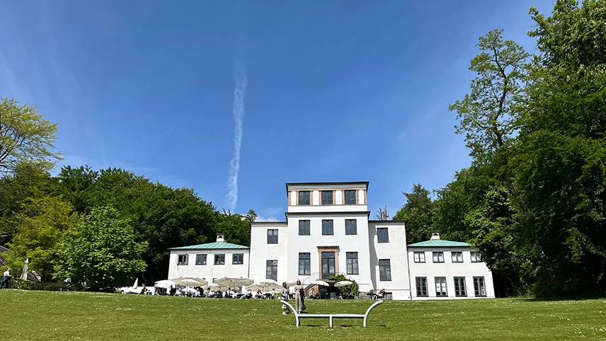 Sophienholm Kunsthal med den vitputsade huvudbyggnaden i mitten och gröna träd runtomkring.