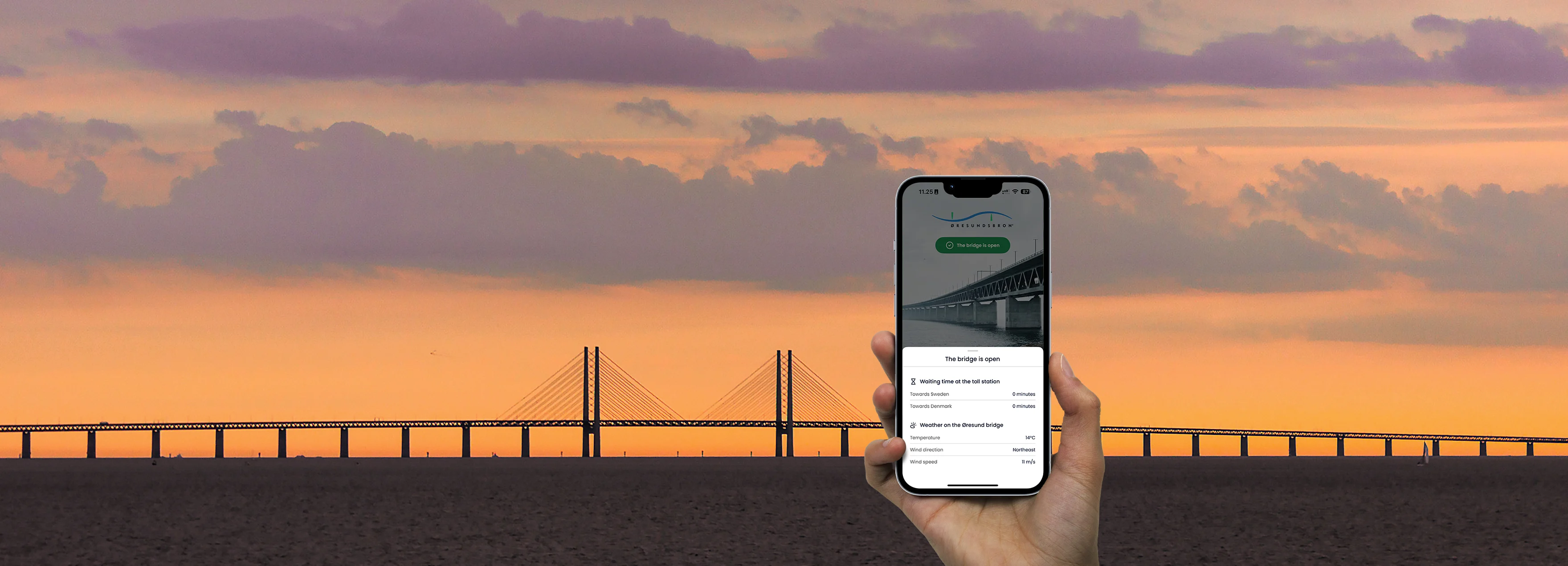 The Øresund Bridge stretches over calm waters under a clear sky at sunset.