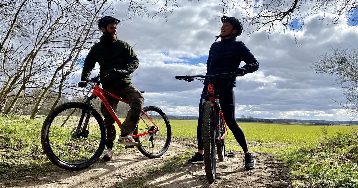 Två cyklister på mountainbike ute i vårskogen.