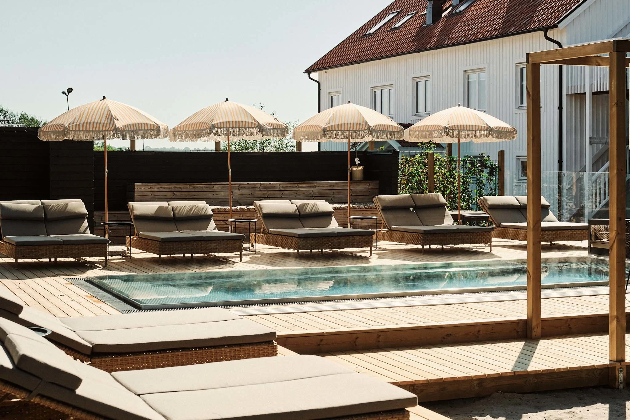 Strandvillans Pool med senge til afslapning og parasoller.