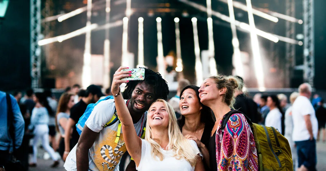 En gruppe unge mennesker tager selfies foran en af scenerne til Malmøfestivalen. 