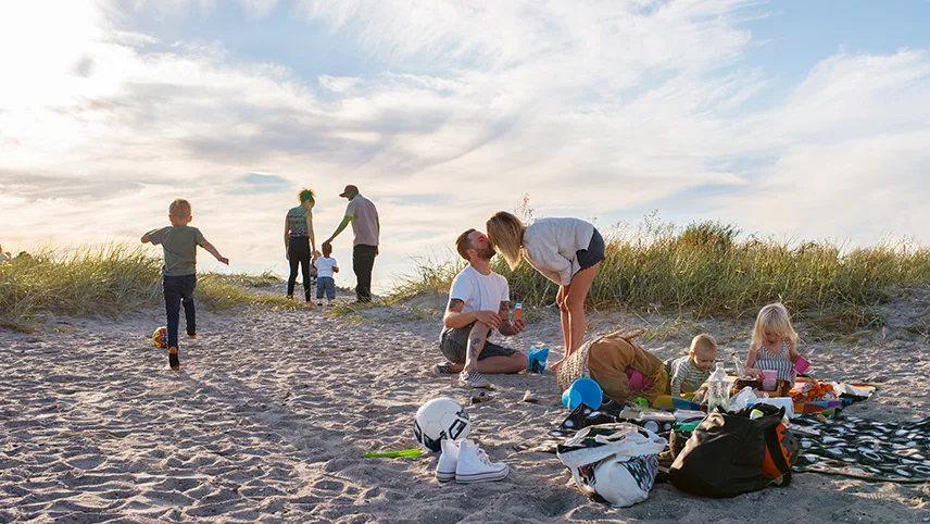 Familj har picknick på stranden och njuter av solen.