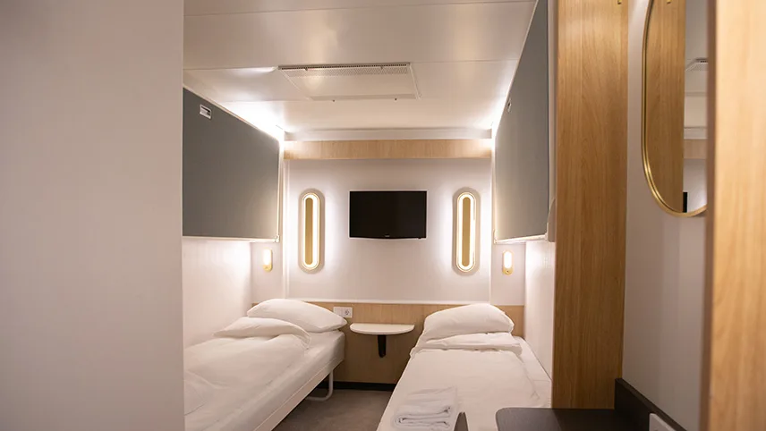 En av standardhytterna med två enkelsängar och ljus inredning i trä och vitt.