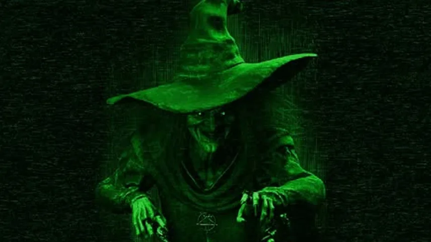 En häxa i grönt ljus mot svart bakgrund från HologramZOO:s Halloween-show.