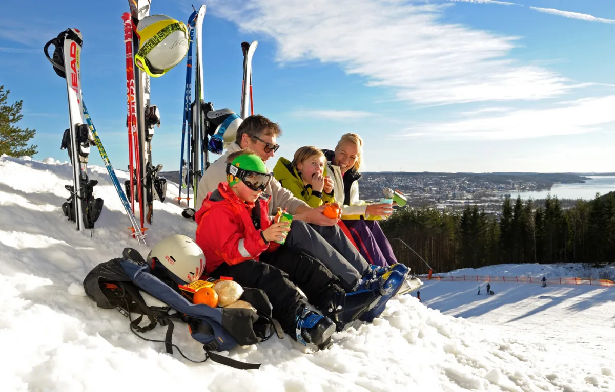 Familie på skiferie i Sverige holder pause i sneen