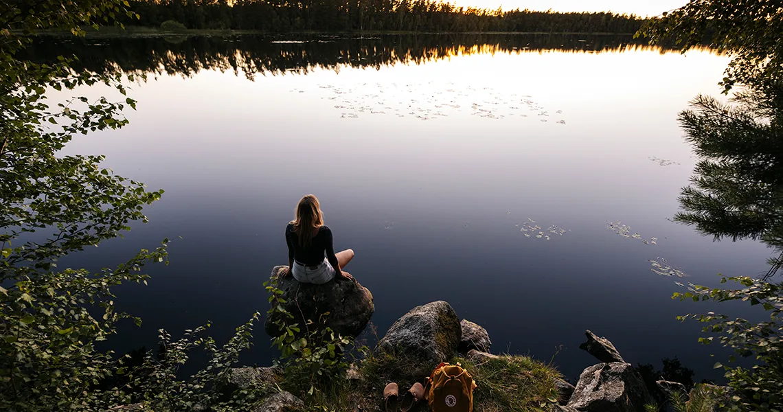 Kvinde ved sø på campingferie i den svenske natur.