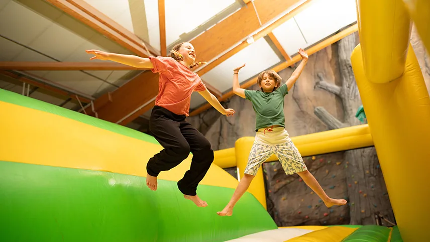 Två barn hoppar jämfota i en hoppborg inne i aktivitetslandet Djungelland.