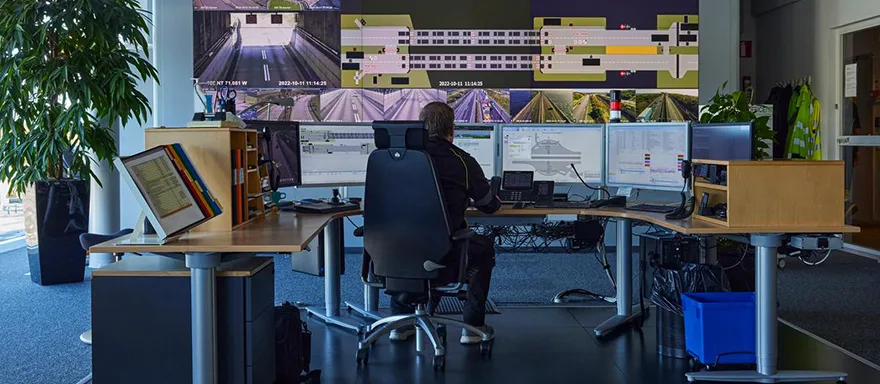 Person at the traffic center sitting at a desk in front of screens with surveillance images.