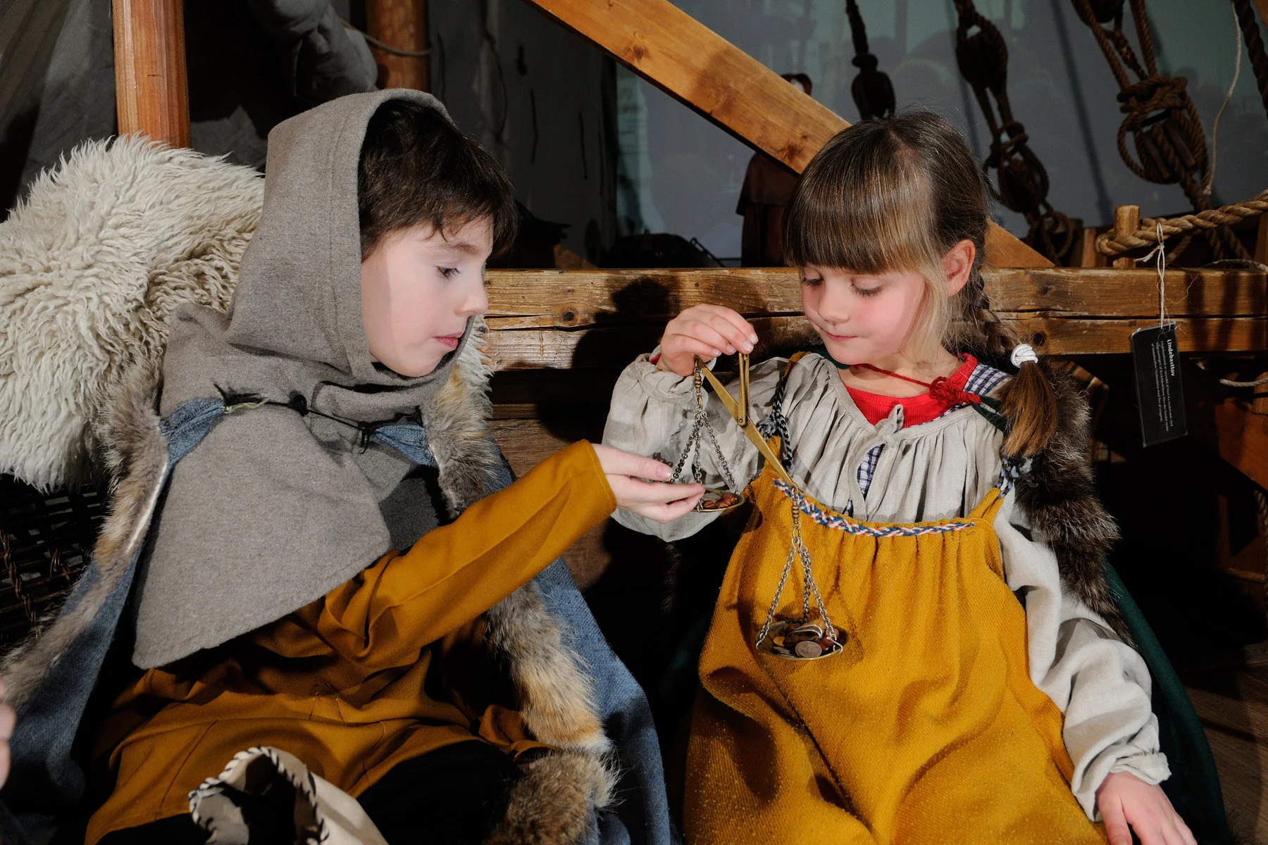 Två barn klär ut sig i vikingatida kläder och utforskar diverse föremål.