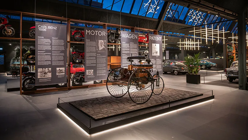 Utställning med cyklar och motorcyklar samt stora skärmar med text.