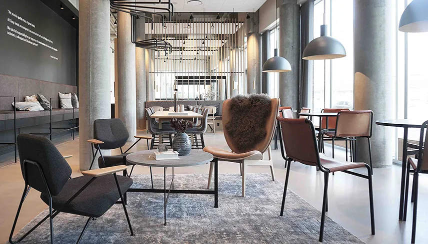 Bild från hotellets lobby med sittgrupper, lampor och glasväggar.