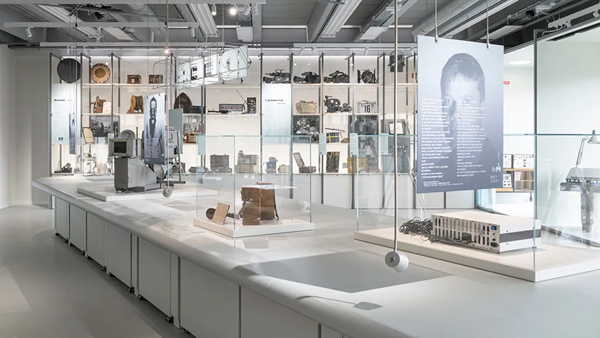 Översiktsbild från utställningen om innovation och uppfinningar inom kommunikation. Här ses ljusa montrar med glasskärmar och föremål utställda i vägghyllor.