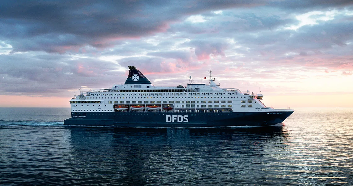 Ett av DFDS fartyg ute på havet i solnedgång.