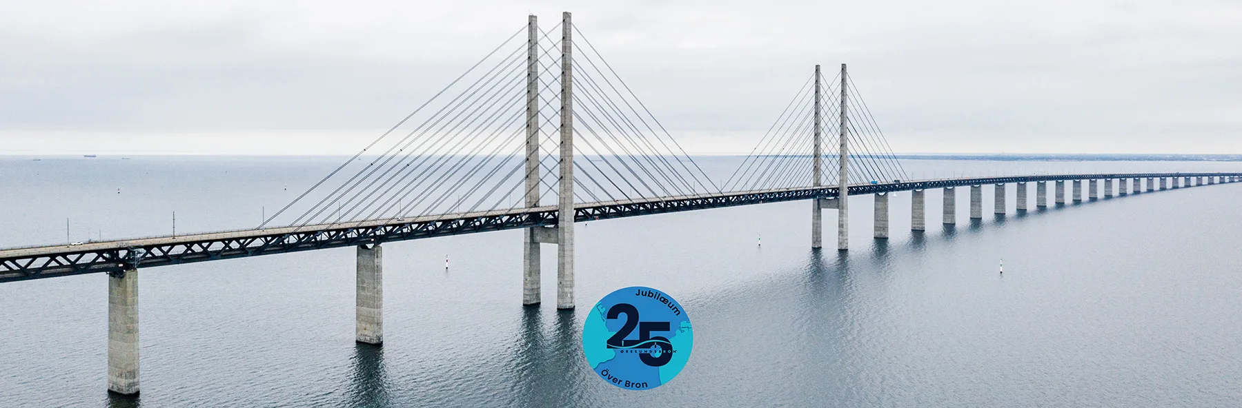 Øresundsbron i sol nedgang med Jubilæums logo foran