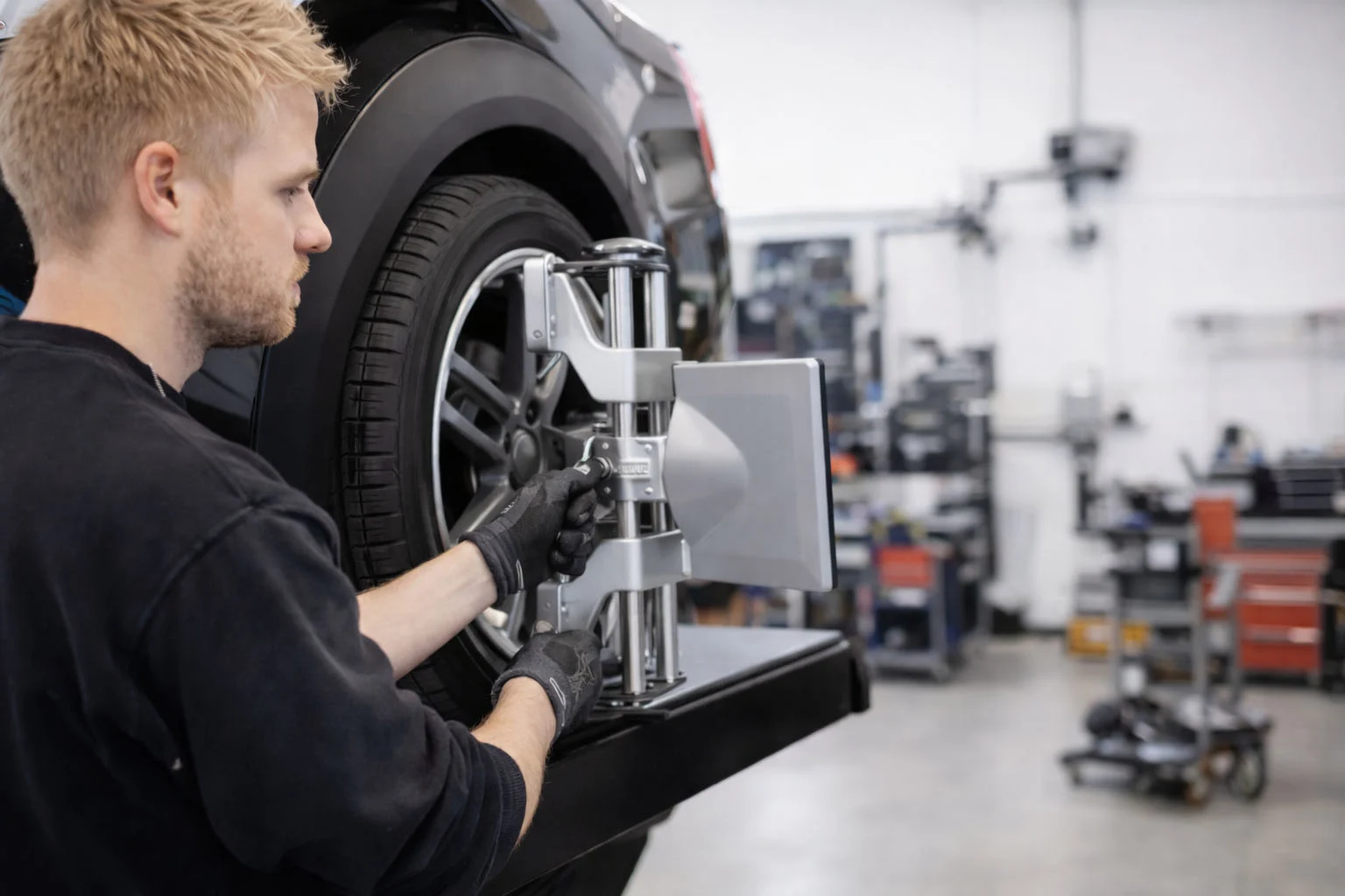 Mand med sorte handsker arbejder på en detalje på en bil.