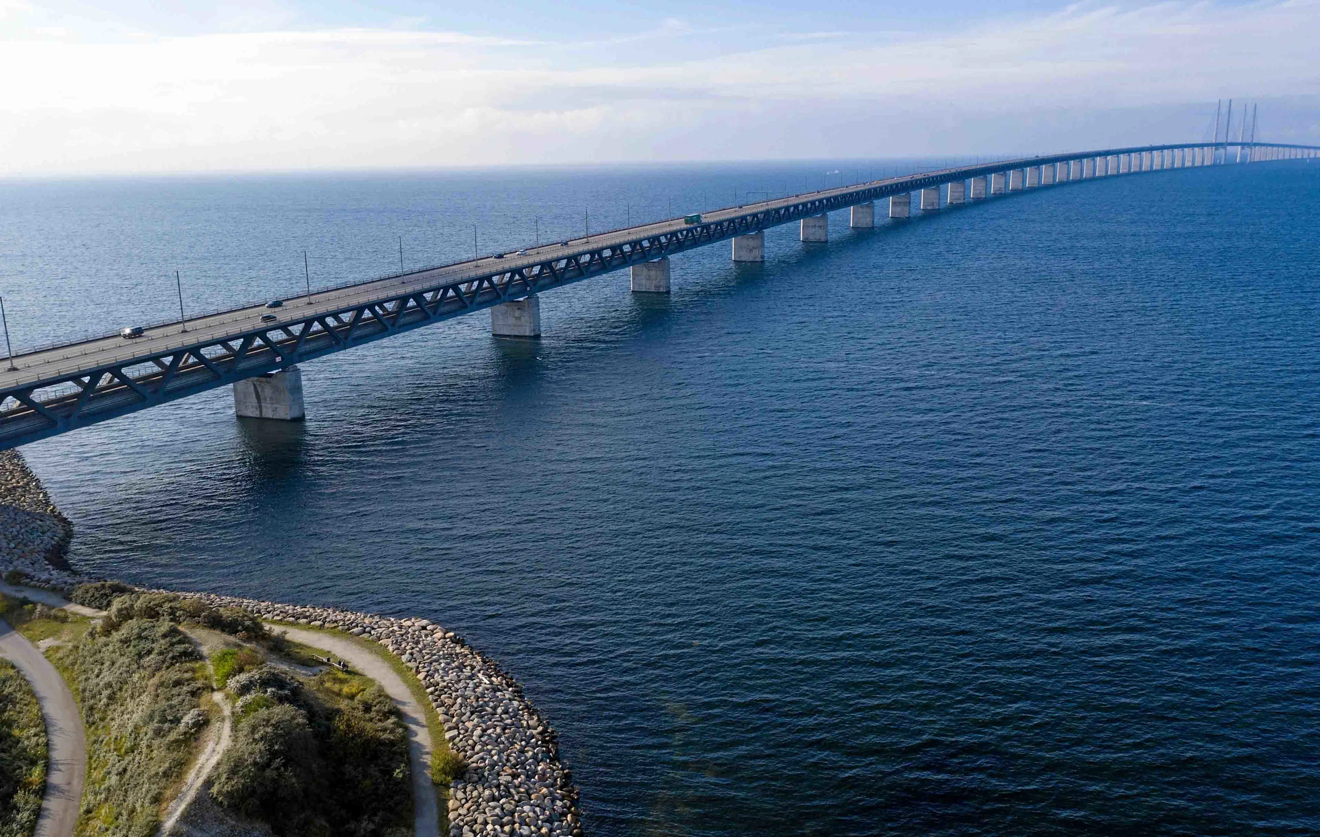 Aerial photo of the Øresund Bridge taken from the Swedish side with an entirely blue sea.