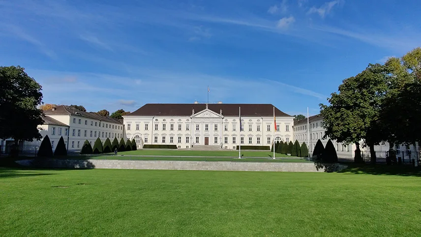 Slottet Bellevue i centrala Berlin. Slottet är vitt och består av tre flyglar med en stor lummig park runt.