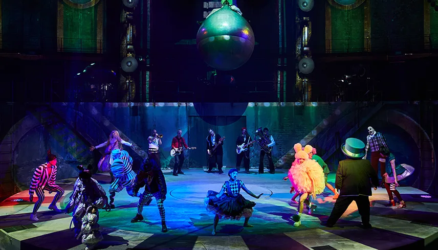 Man ser den runda scenen och ett stort antal artister som dansar i en stor cirkel. Alla har dramatiska kostymer och vissa har ryggen mot, medan andra står med ansiktet vänt mot kameran.