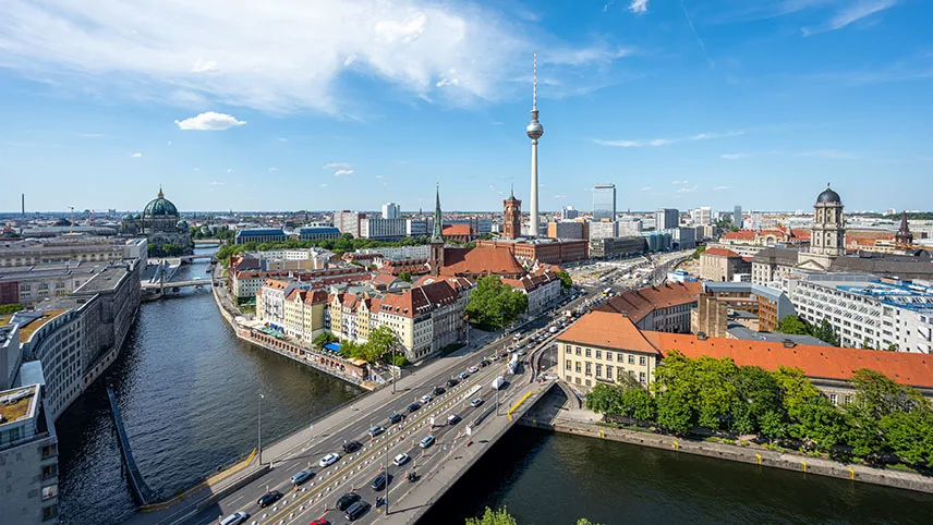 Flygfoto över Berlins stadskärna med floden Spree, en bro och TV-tornet i bakgrunden.