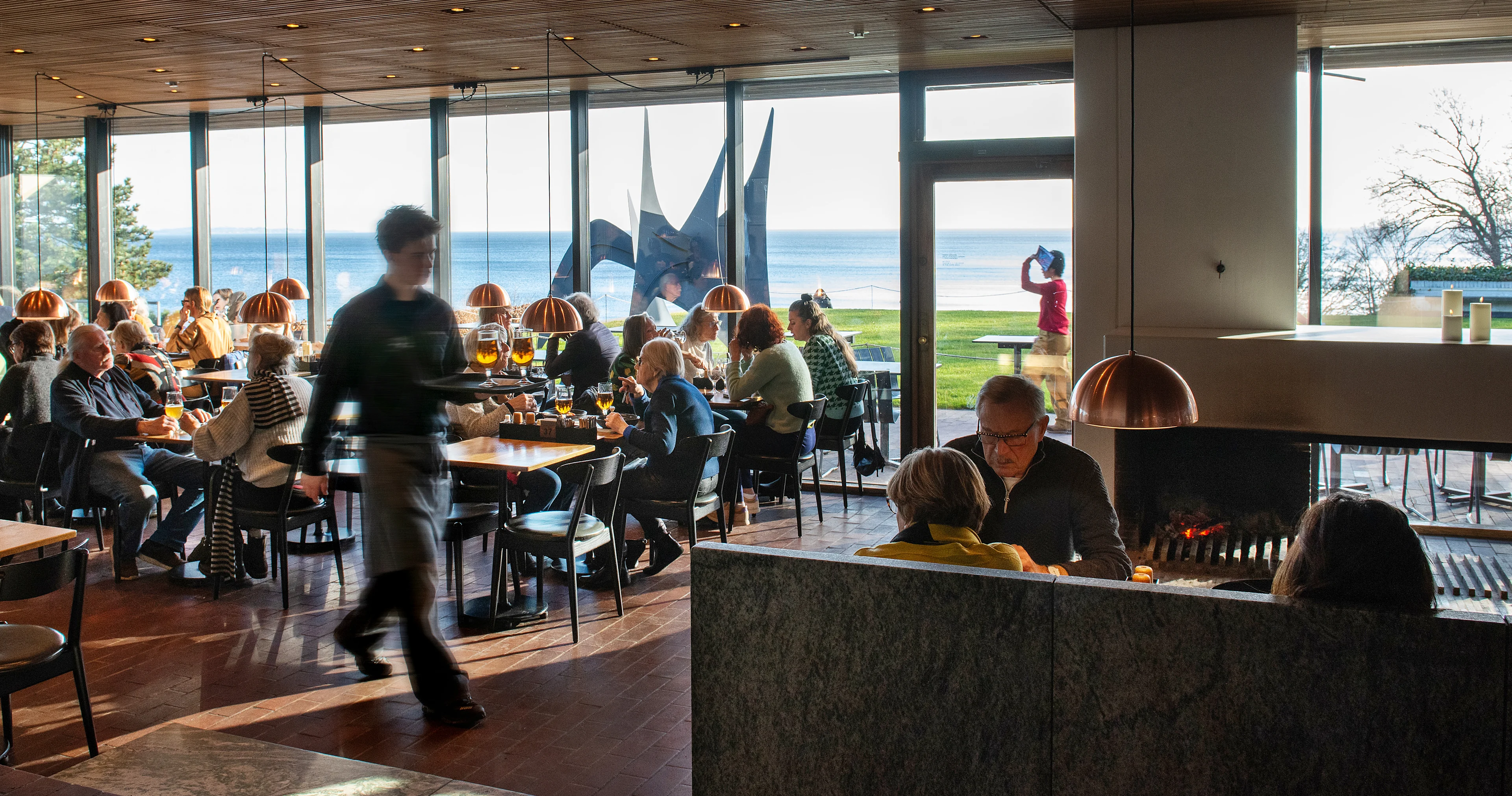 Louisianas Café med gäster som sitter vid upplysta bord. En servitör med en bricka går genom rummet.