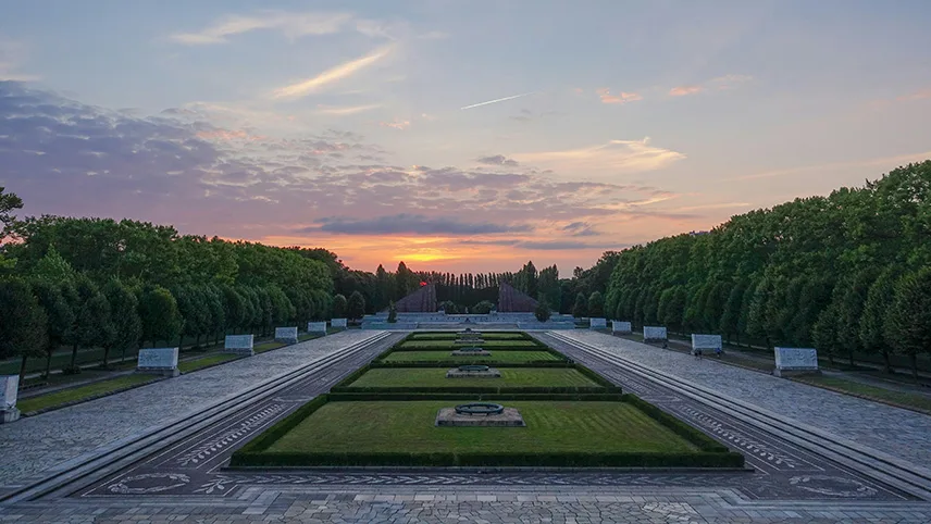 Översiktsbild från Treptower Park vid solnedgång. I bakgrunden syns en vacker kvällshimmel, träd och en vacker park.