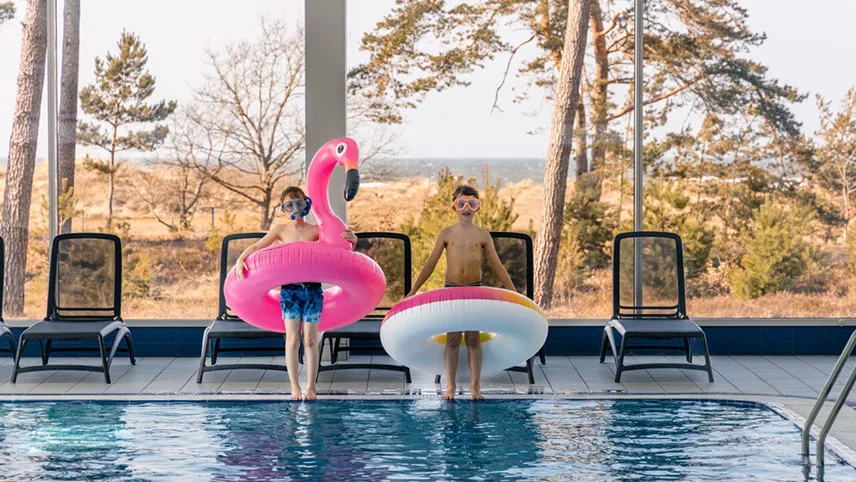 To børn leger i poolen hos Hotel Riviera Strand ked baderinge og udsigt over stranden.
