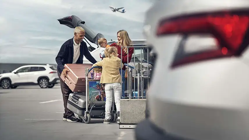En familj lastar ur väskor ur bilen på parkeringen vid flygplatsen.
