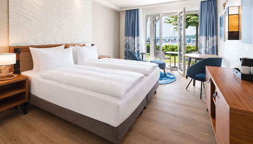 Ett av hotellets rum med dubbelsäng, sittgrupper och terrass ut mot havet.