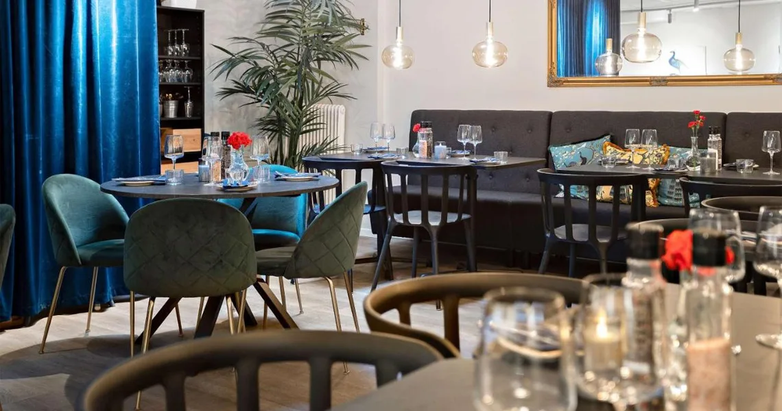 Restauranten hos Palm Tree Hotel i Trelleborg. Her ses hyggelig indretning med bløde stole og bænke, fine farver og pæn borddækning.
