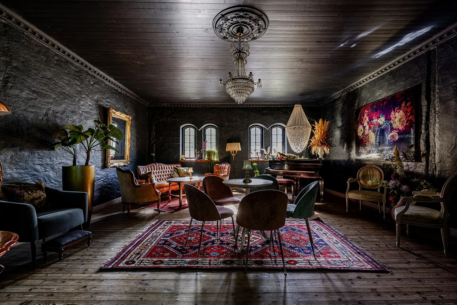 Idala Gårds lounge område med sofaer og stole. Farverne er meget mørke og her er farverig kunst på væggen samt farverigt gulvtæppe.