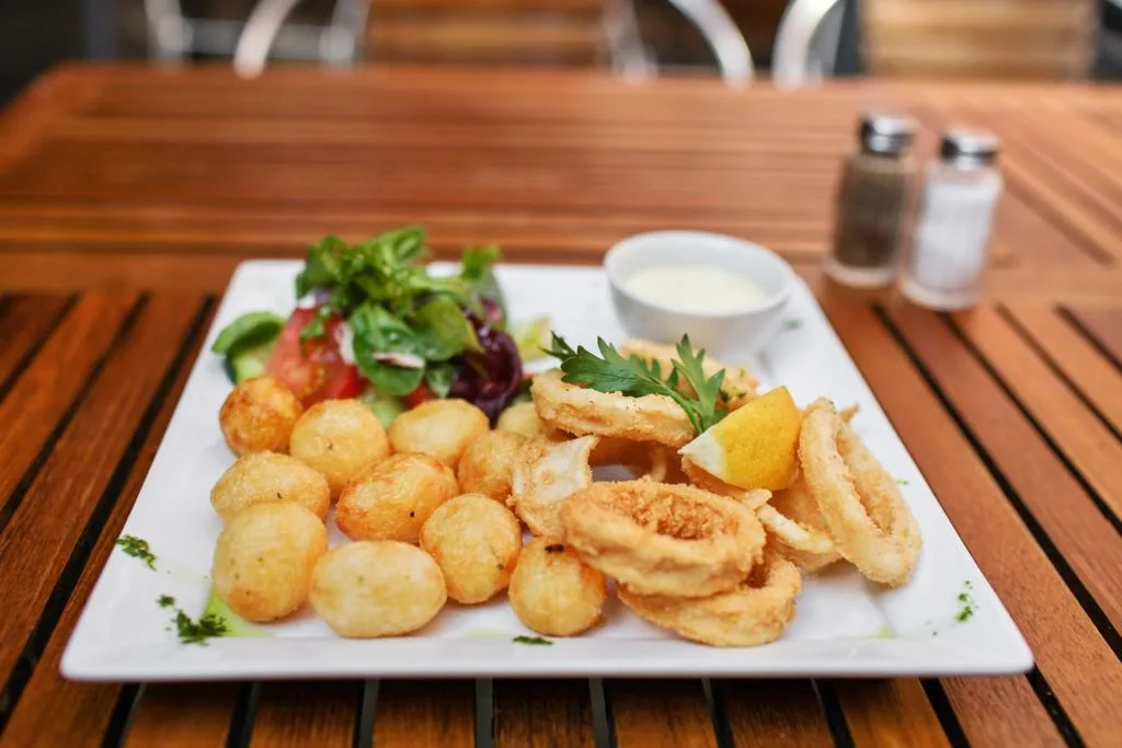 Restaurant Akropolis i Malmø serverer et godt udvalg af græske retter. Her ses fritterede kartoffler og blæksprutteringe med grønt til.