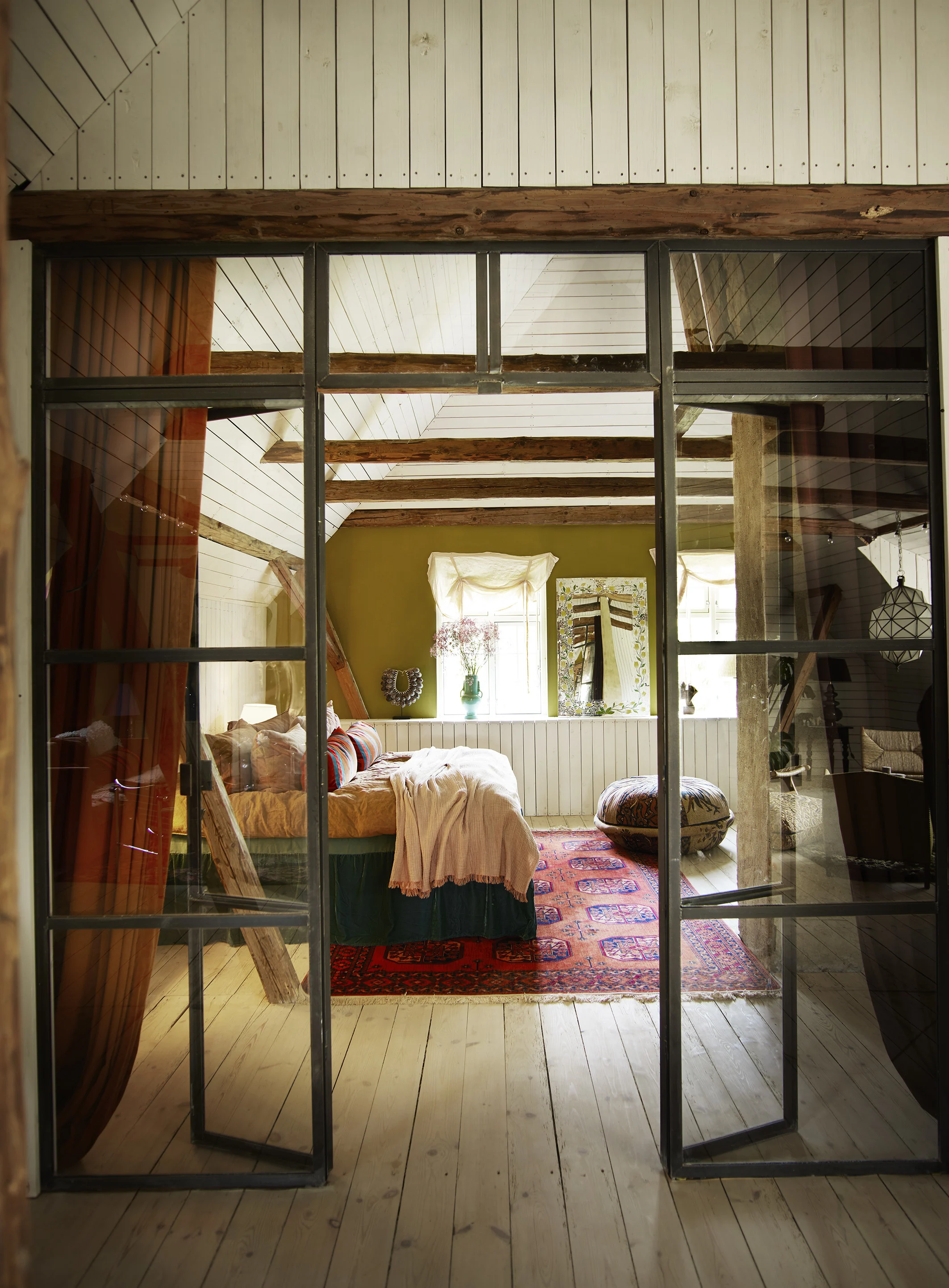 Ett av rummen hos The Norrmans Farmhouse, sett genom en glasdörr med dubbelsäng i fokus.