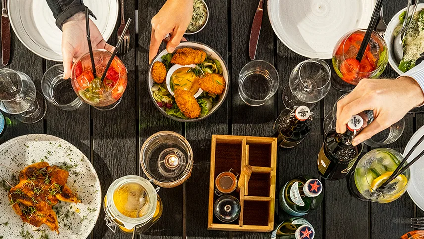 Hotel Continental du Suds aftensmad i restauranten, bestående af forskellige snacks, øl, drinks og mennesker der rækker ud efter maden.