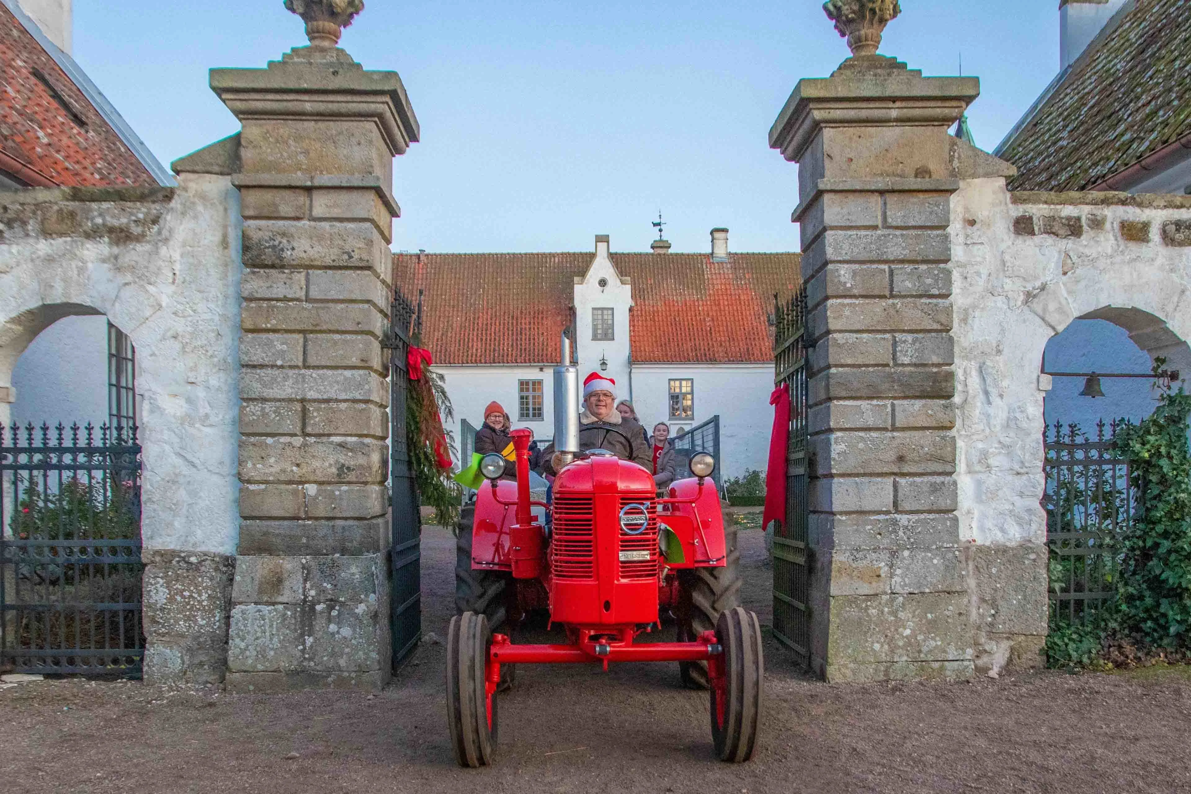 Jul på Bosjökloster slott. En traktor med passagerer i nissehuer kører ud gennem portene.